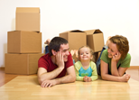 photo of parents with toddler daygter laying on the floor smiling with moving boxes behind them